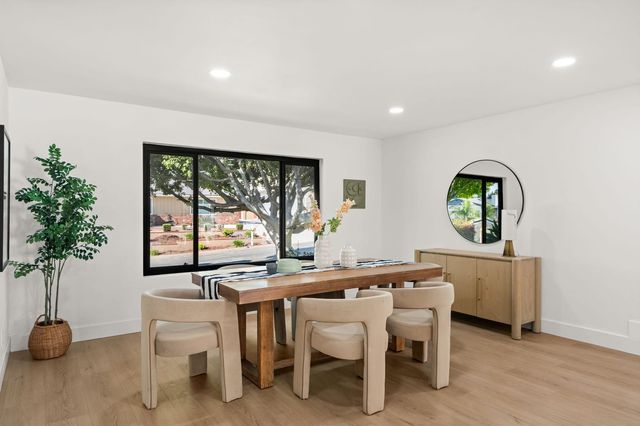 Dining room with a wood table, upholstered chairs and a black-framed window