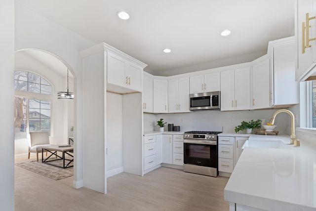 White kitchen with a stainless range and a view through to the dining area