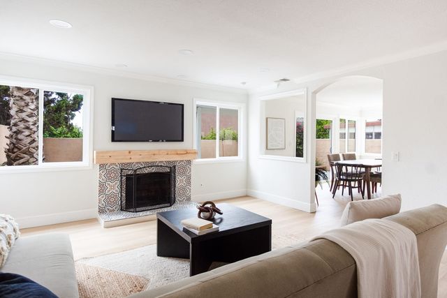 Living room with a tiled fireplace, a mounted television and a dining nook beyond