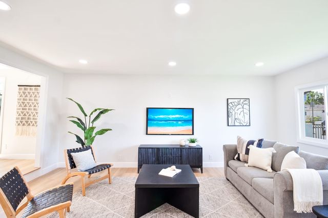 Living room with a long low media console, a gray sofa and two woven chairs