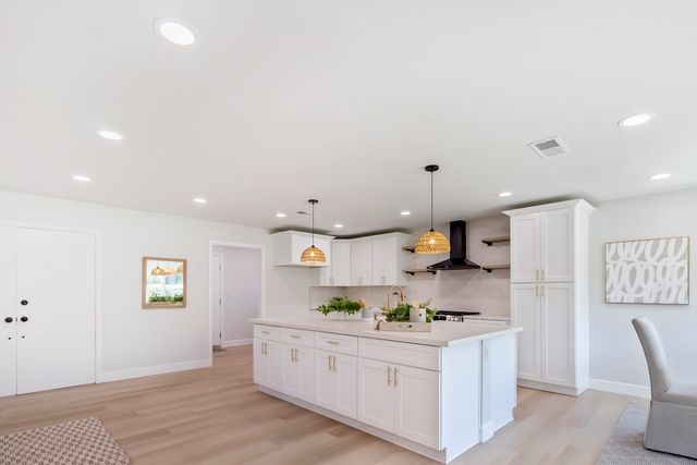 Kitchen with a white island, pendant lights and a range hood