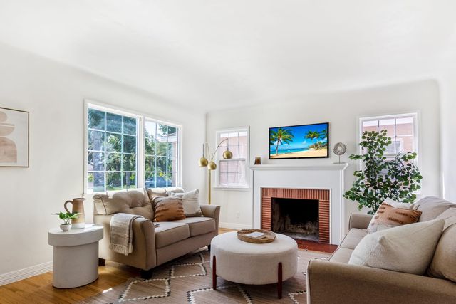 Living room with a brick fireplace, a sofa and two windows
