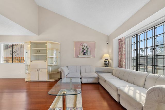 Living room with a sectional sofa, a glass display cabinet and tall windows