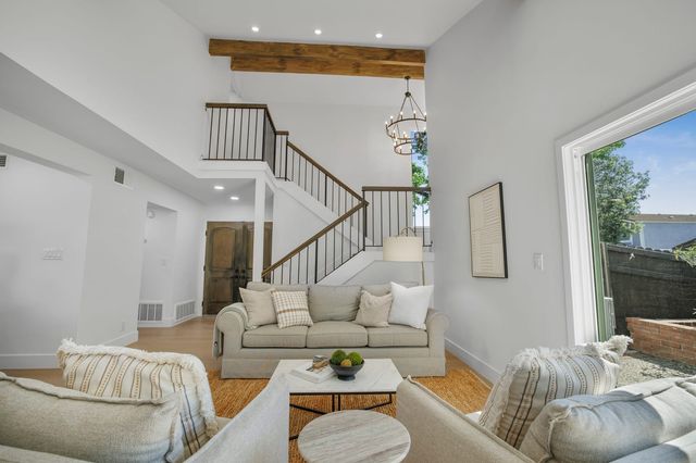 Two-story living room with a staircase, beams and glass doors