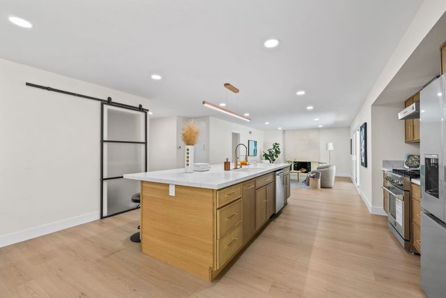 Kitchen with a long island, wood cabinets and a sliding barn door