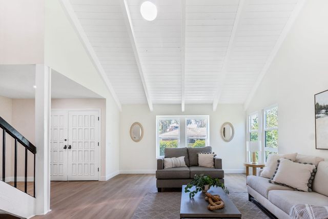 Vaulted living room with a sofa, a staircase and double front doors