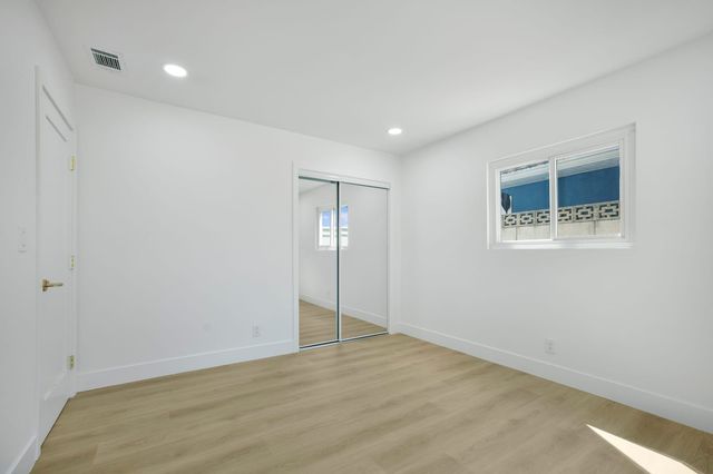 Empty bedroom with a mirrored closet and a window