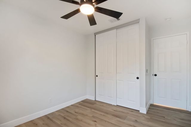 Empty bedroom with a ceiling fan and closet doors