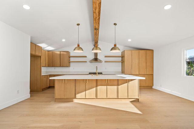 Kitchen with a long island, three pendant lights and wood cabinets