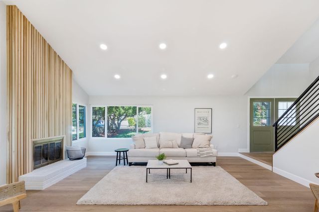Vaulted living room with a slatted fireplace wall and a staircase