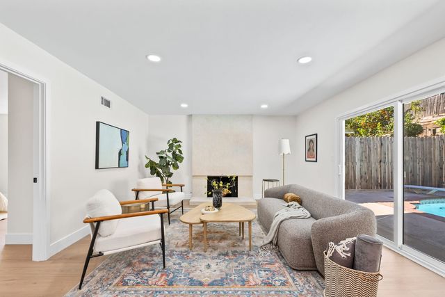 Living room with a stone fireplace and a sliding door to a pool